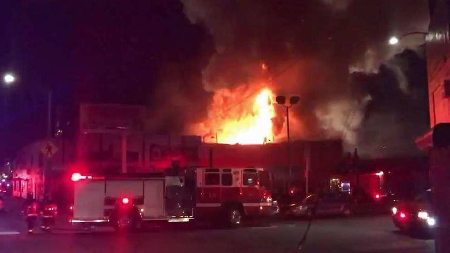 Un camión de bomberos llega a la zona en la que el fuego sobresale por encima del edificio.