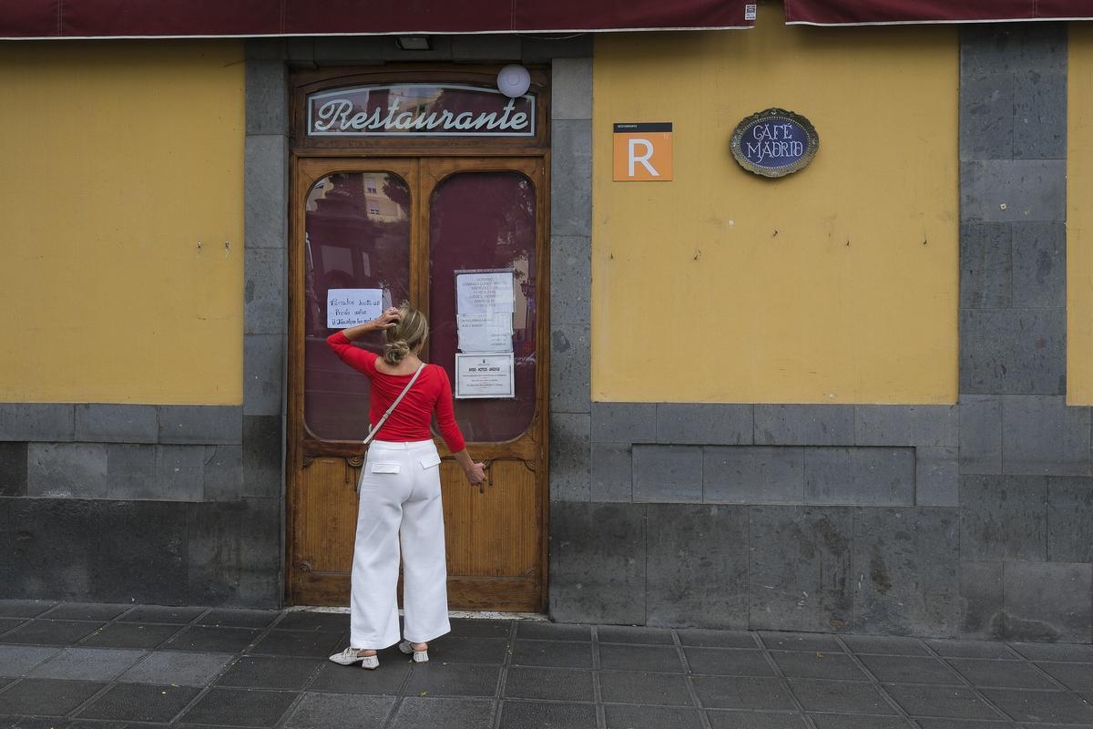 Una paseante se detiene ante la fachada del Café Madrid a leer la orden de cierre.
