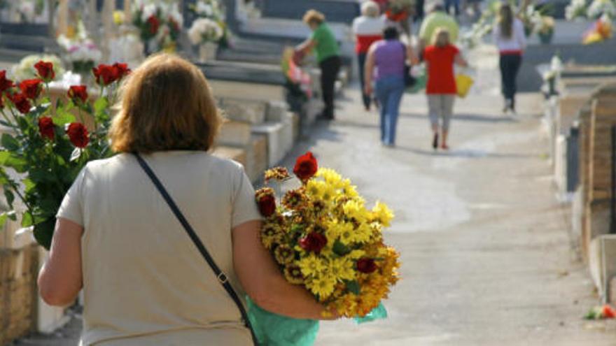 Una mujer se dispone a depositar flores en el cementerio de Cartagena