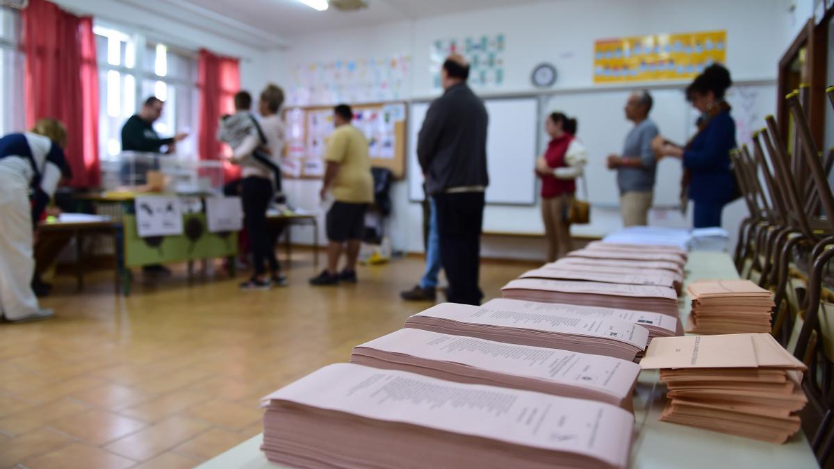Papeletas dispuestas y colas de votantes en un colegio electoral de Plasencia.