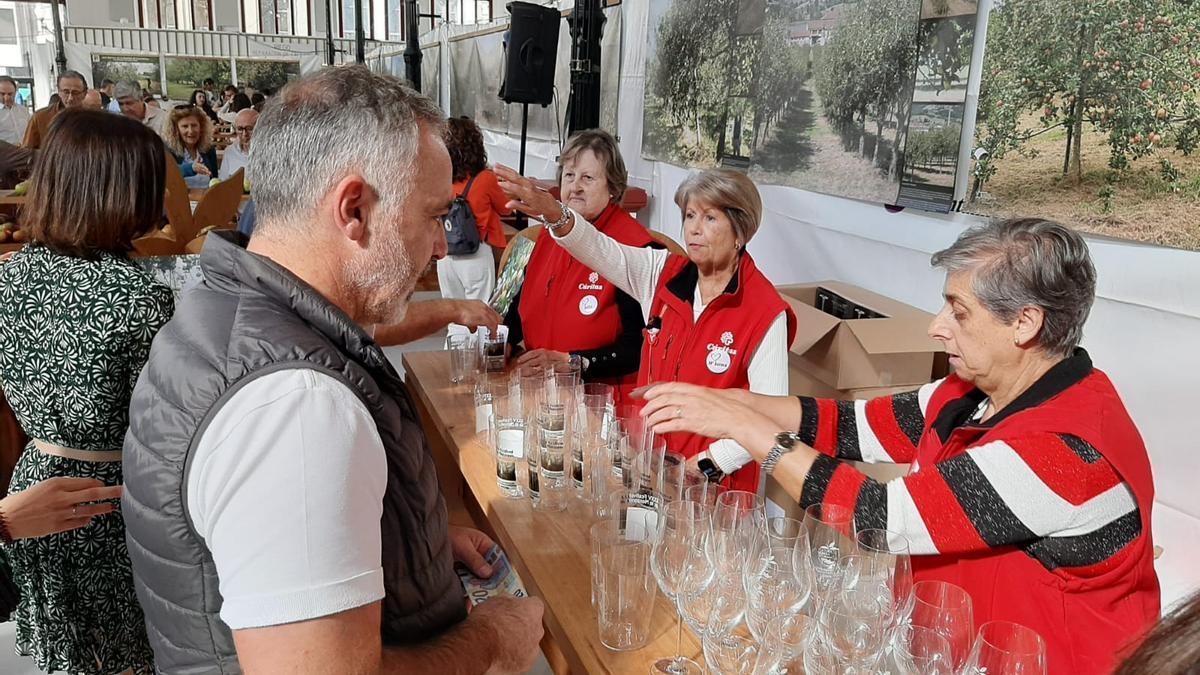 Por la izquierda, Julita Fernández, María Aurora Gancedo y Ana Isabel González en el puesto de venta de vasos conmemorativos del Festival de la Manzana de Villaviciosa