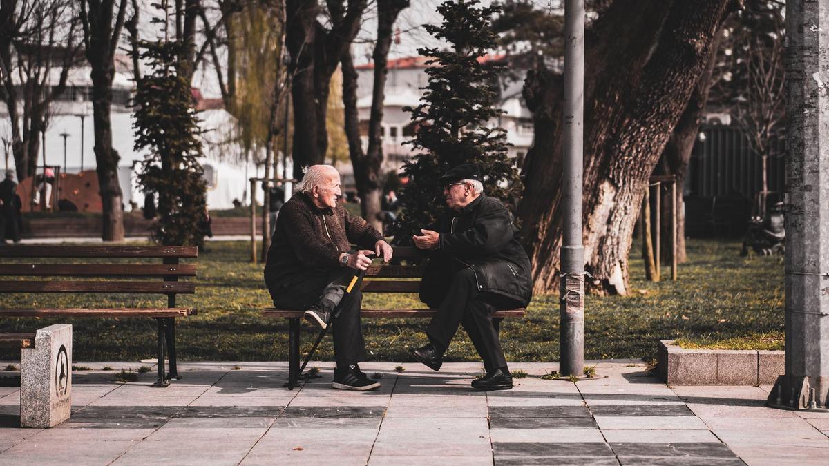 Dos hombres mayores conversando en un banco
