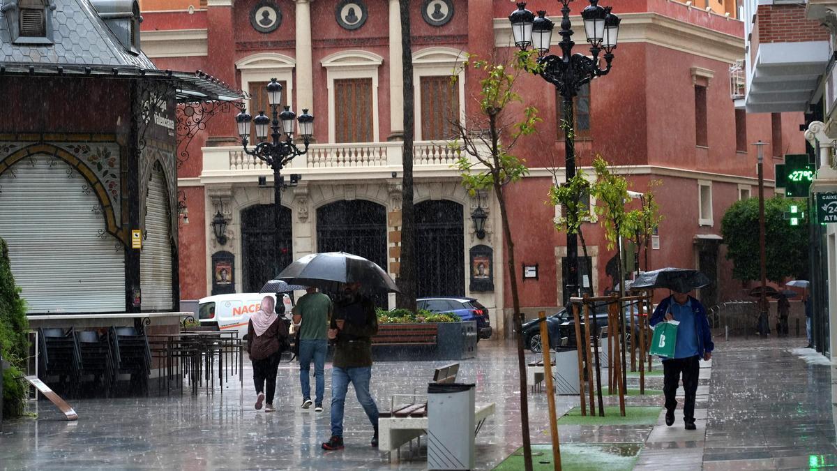 Gente pasea con paraguas este lunes en la plaza de La Paz en Castelló.