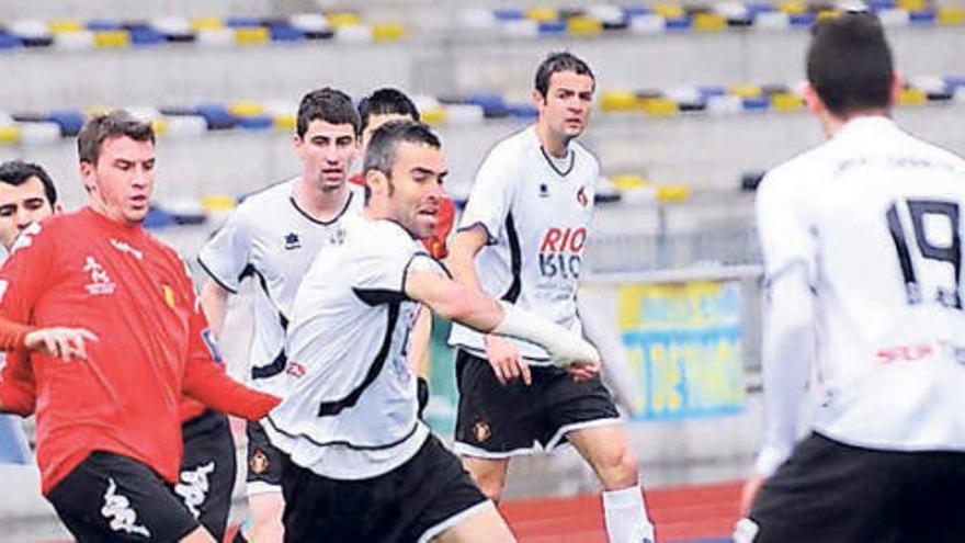 Una acción del duelo ante el Luarca con un único aficionado en la grada del Hermanos Antuña, al fondo.