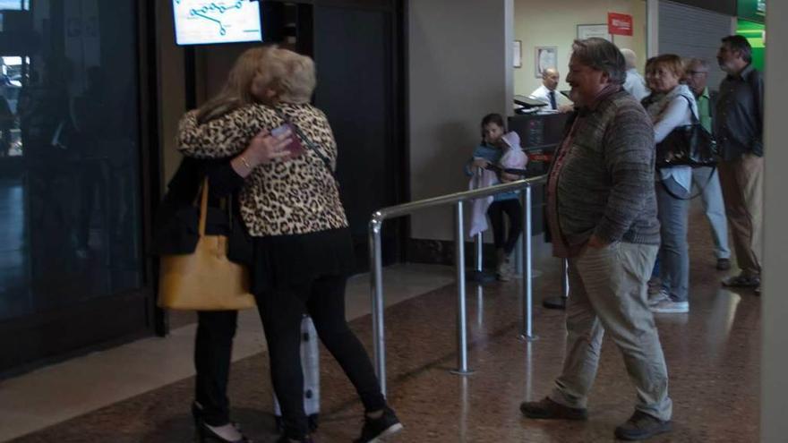 Arriba, dos familiares se abrazan tras su encuentro en el aeródromo asturiano. A la derecha, viajeros a las puertas de las instalaciones de Santiago del Monte.