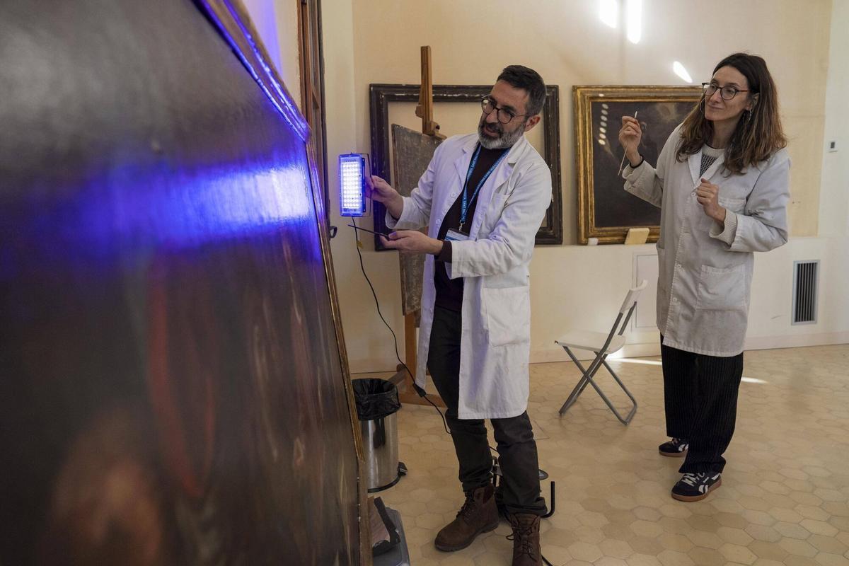 Irene Panadés y David Silvistre ecaminan con luz ultravioleta la capa de barniz de una de las obras.