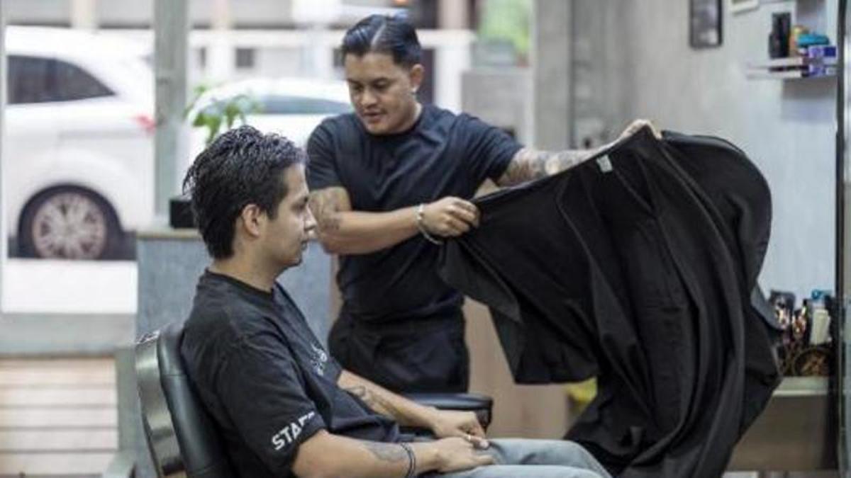 Juan preparando a uno de sus clientes para cortarle el pelo