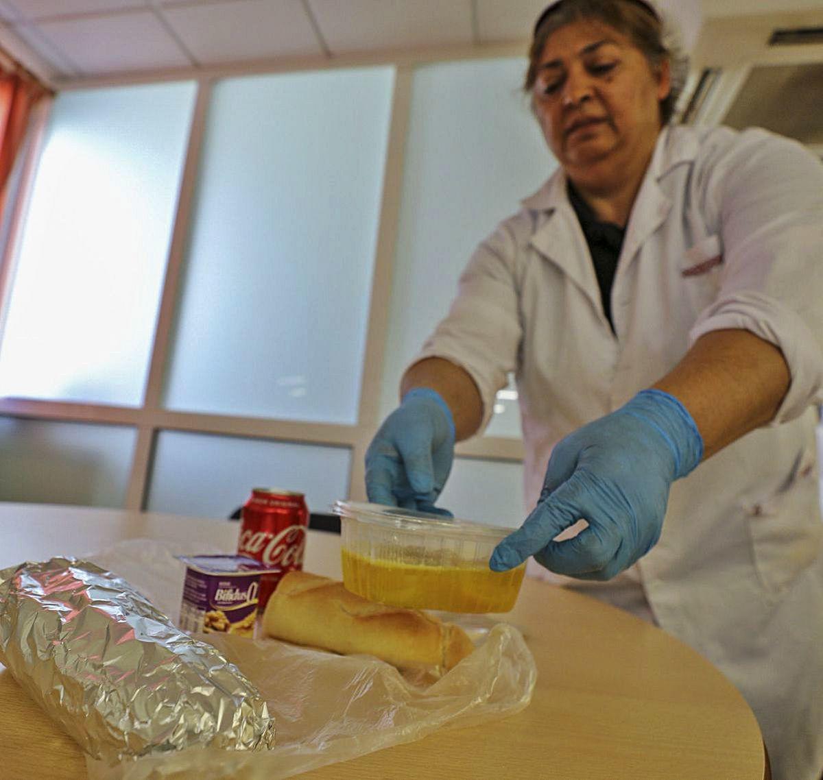 Una cocinera deja un túper con caldo en la bolsa del picnic.