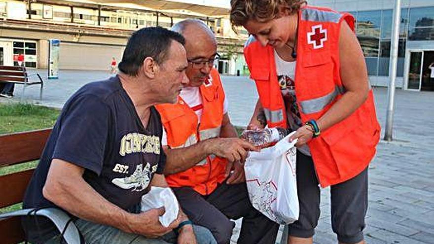 Voluntaris de la Creu Roja reparteixen un kit a en Vicente, que viu al carrer des de fa dos anys.