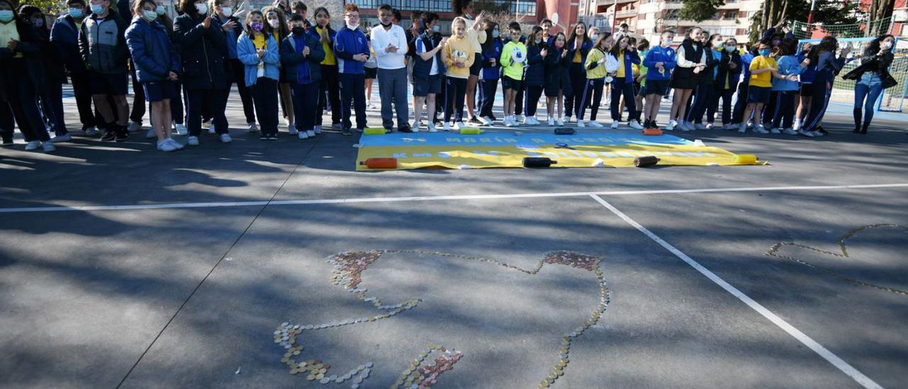 Los alumnos, junto a la paloma de la paz dibujada con monedas.