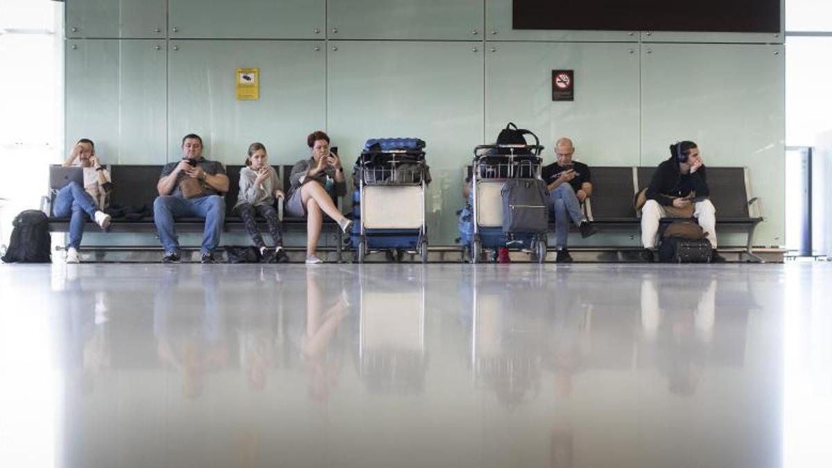 Pasajeros a la espera en el aeropuerto de El Prat Foto Ferrán Nadeu