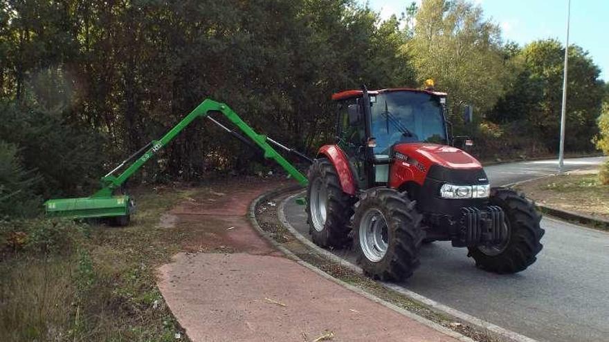 Un tractor desbroza un vial del polígono empresarial.