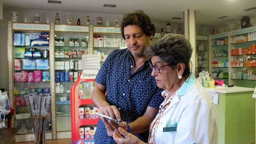 Araceli de la Fuente, con uno de sus hijos, en la farmacia que regenta.