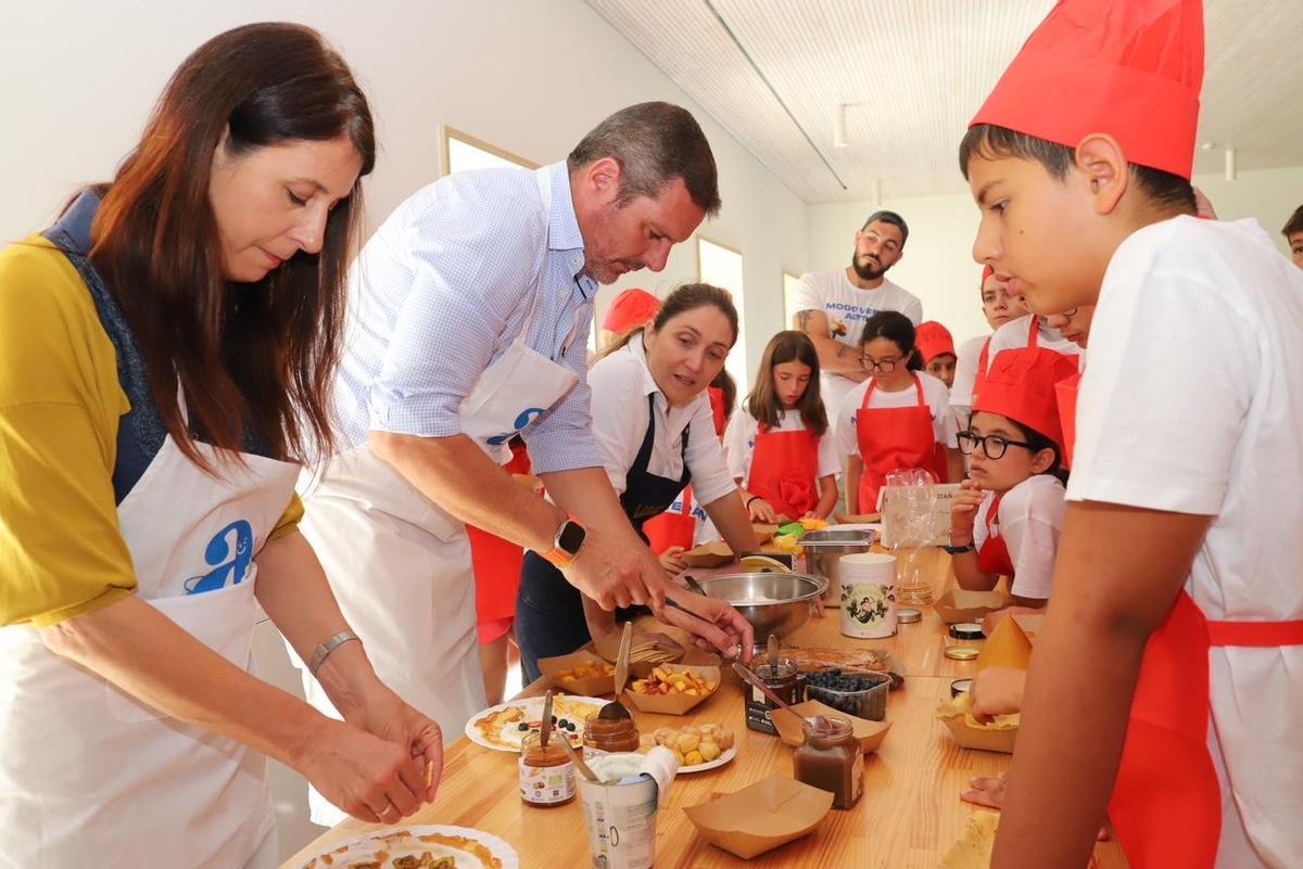 María José Gómez, esquerda, e José López, cos cativos de campamento, nun taller de cociña.