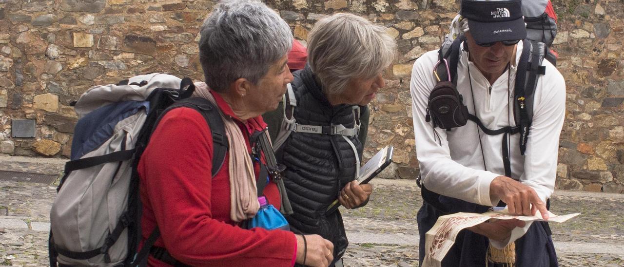 Tres viajeros consultan un mapa del casco histórico de Cáceres.