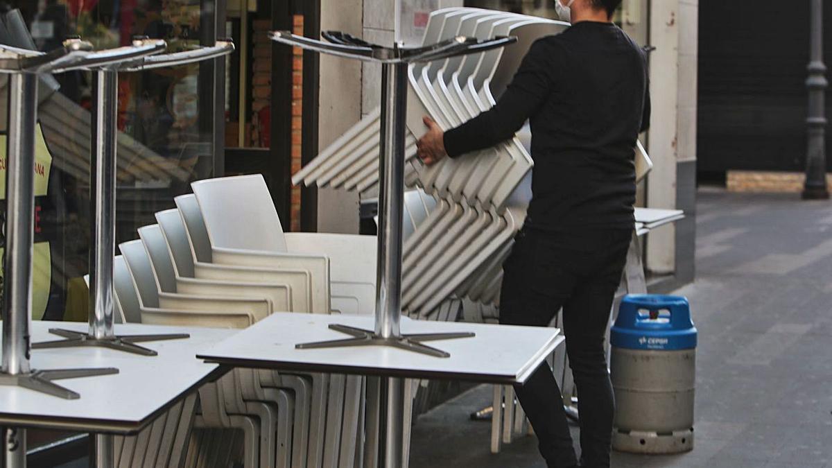 Un trabajador recoge las mesas de una terraza, días antes del cierre obligatorio de la hostelería.