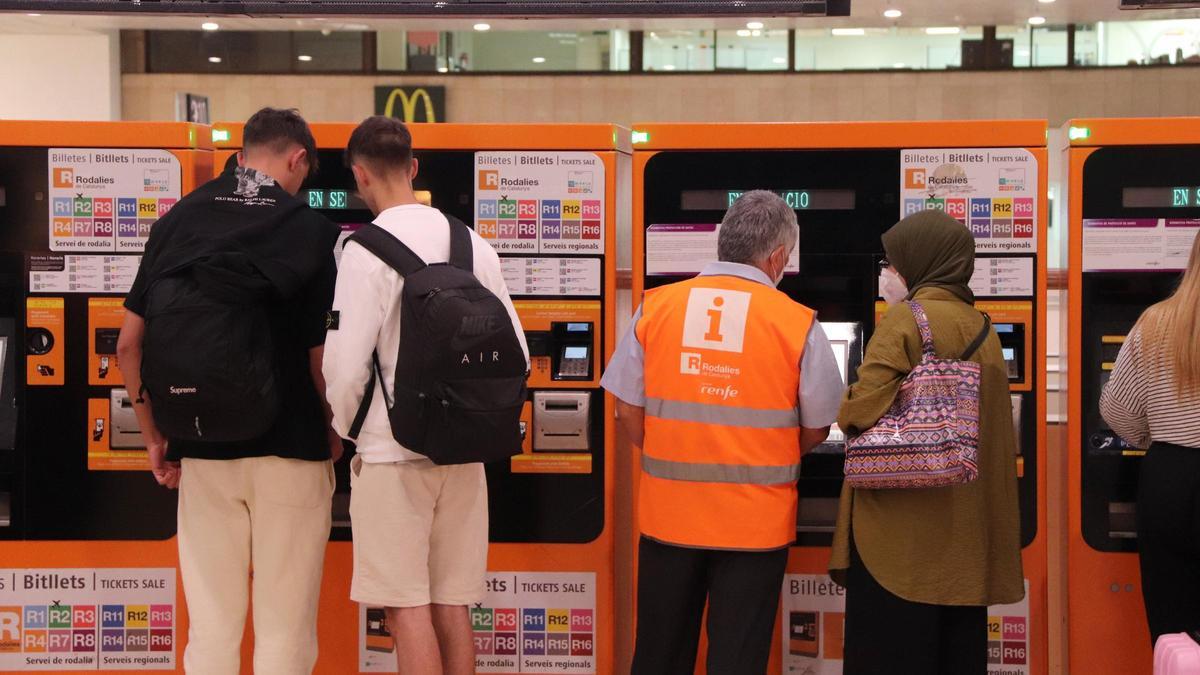 Diverses persones a les màquines d'autovenda de Rodalies de l'estació de Sants de Barcelona el primer dia en vigor dels abonaments gratuïts