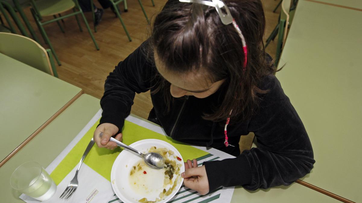 Una niña come en el comedor escolar.