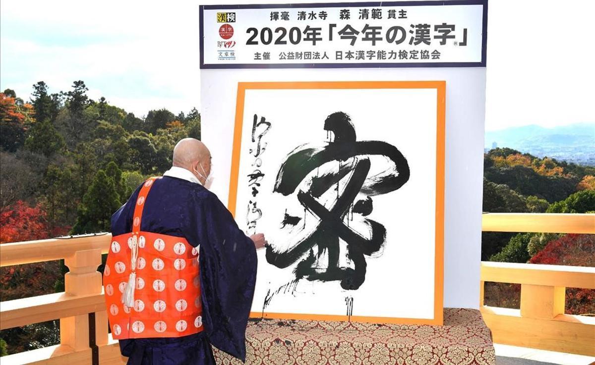 This picture received from Jiji Press shows Seihan Mori  master of the ancient Kiyomizu temple  using calligraphy to write the Chinese character  known in Japan as  kanji   for  mitsu   which was selected as the single best kanji to symbolise the year of 2020 at the temple in Kyoto  western Japan  on December 14  2020  (Photo by STR   JAPAN POOL   AFP)   Japan OUT