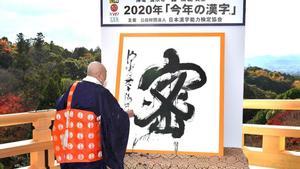 This picture received from Jiji Press shows Seihan Mori  master of the ancient Kiyomizu temple  using calligraphy to write the Chinese character  known in Japan as  kanji   for  mitsu   which was selected as the single best kanji to symbolise the year of 2020 at the temple in Kyoto  western Japan  on December 14  2020  (Photo by STR   JAPAN POOL   AFP)   Japan OUT