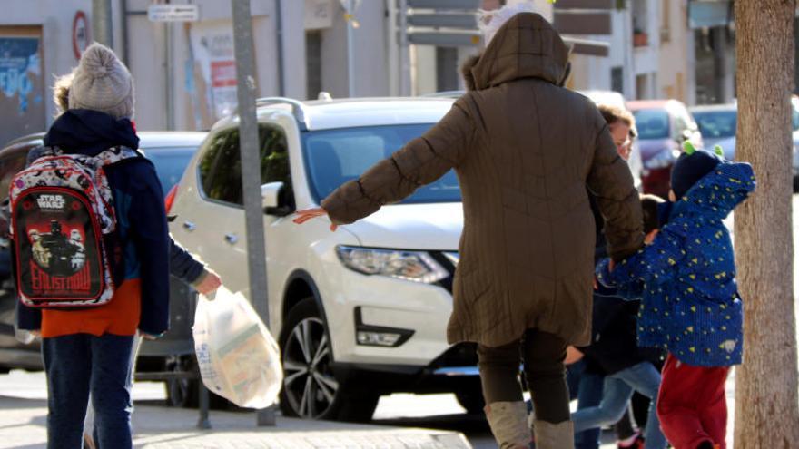 Una dona i de dos menors caminant a Valls enmig d&#039;un fort vent