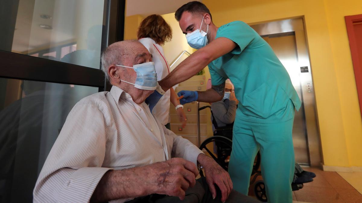 Un enfermero vacuna a un anciano en un centro geriátrico.