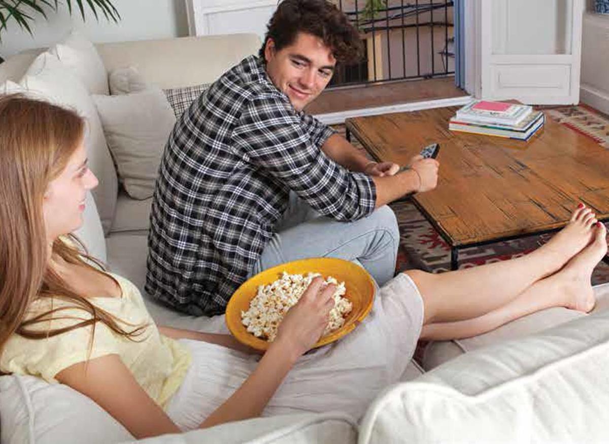 Una pareja se dispone a ver la televisión en el salón de su casa.