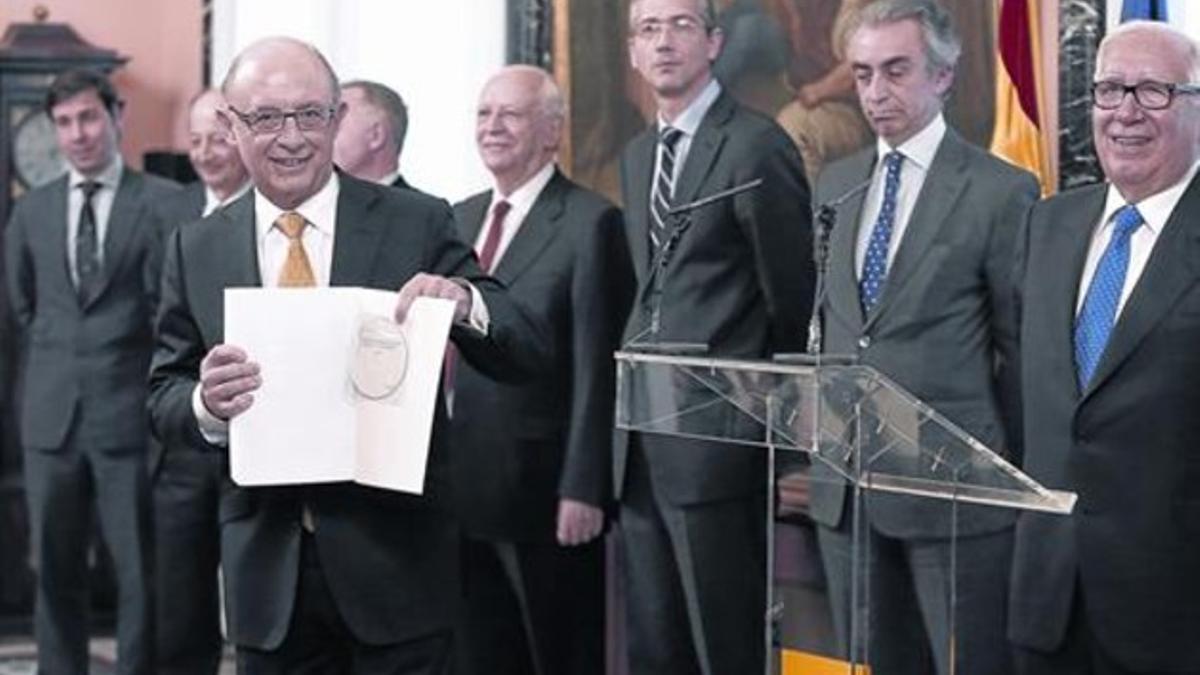 El ministro de Hacienda, Cristóbal Montoro, muestra el informe recibido.
