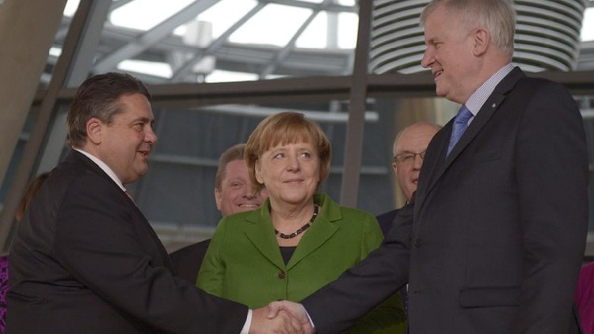 Merkel observa el saludo entre el líder de la CSU, Horst Seehofer (derecha) y el líder del SPD, Sigmar Gabriel, este miércoles en Berlín.