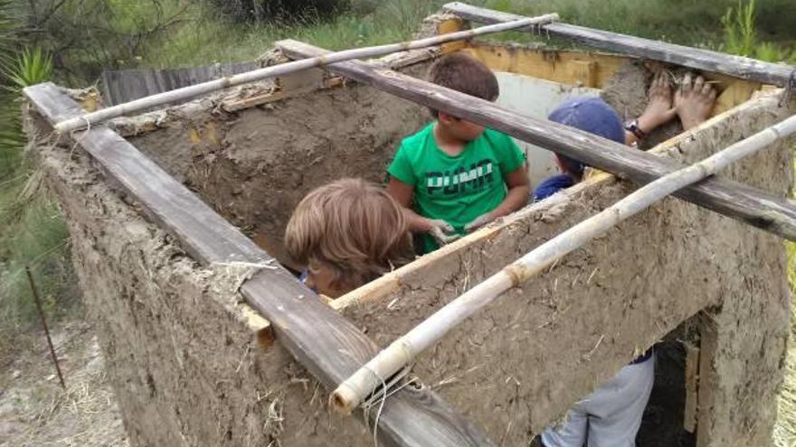 Uno niños construyendo la cabaña en el taller de la escuela de verano del Parc de la Vall d&#039;Albaida.