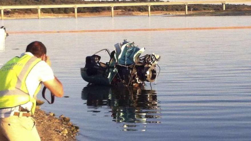 Un guardia civil fotografía los restos del helicóptero caído al pantano de Valmayor.