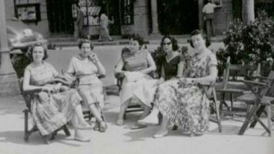 Un grup de dones assegudes en cadires a la Rambla de Figueres, en una imatge històrica.