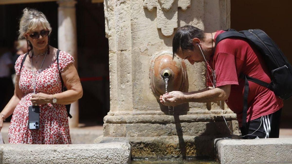 Un hombre se refresca del calor de Córdoba en el Patio de los Naranjos