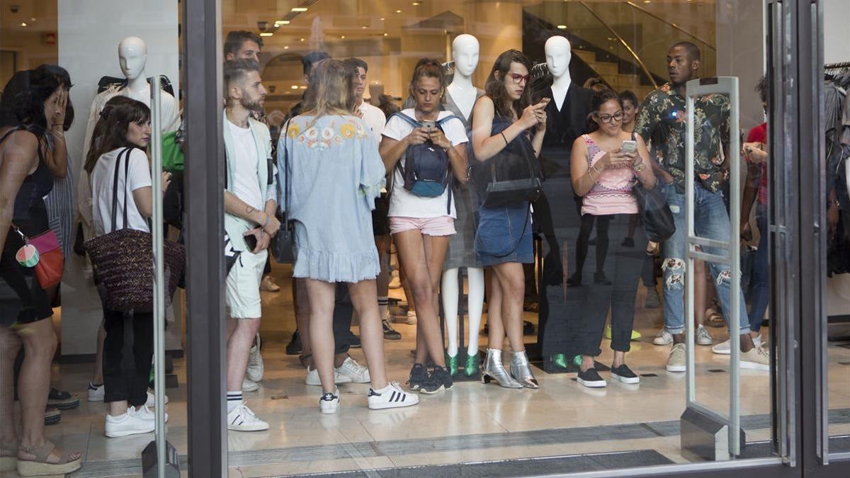 Unas personas se refugian dentro de un comercio en paseo de Gràcia.