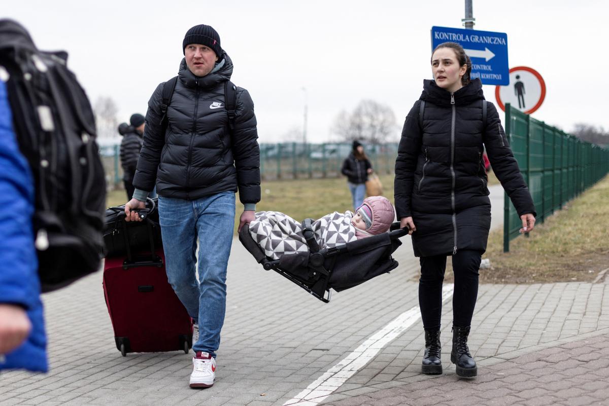 Una pareja con su hijo en Medyka (Polonia), tras cruzar la frontera con Ucrania.