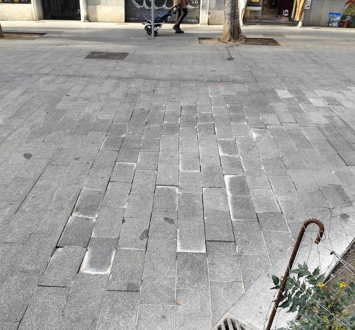 Adoquines en mal estado en la acera del cruce de la calle Joan Torras con Gran de Sant Andreu.