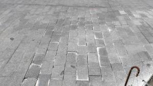 Adoquines en mal estado en la acera del cruce de la calle Joan Torras con Gran de Sant Andreu.