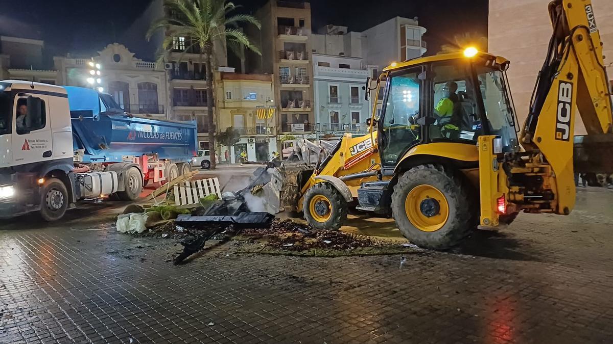 Una máquina recoge los restos de la falla en la plaza.