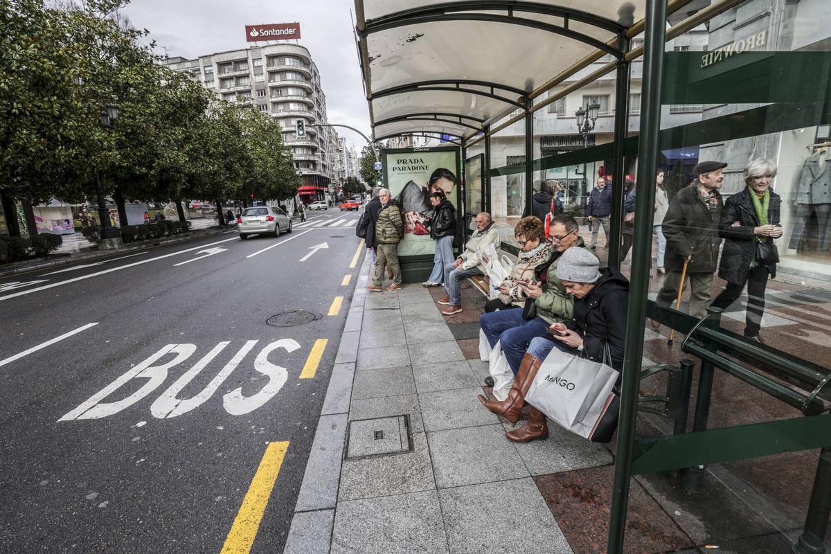 Usuarios esperando al autobús urbano en una parada de Uría.
