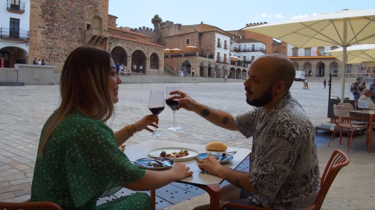 Dos viajeros disfrutan de la gastronomía cacereña en la plaza Mayor de la ciudad.