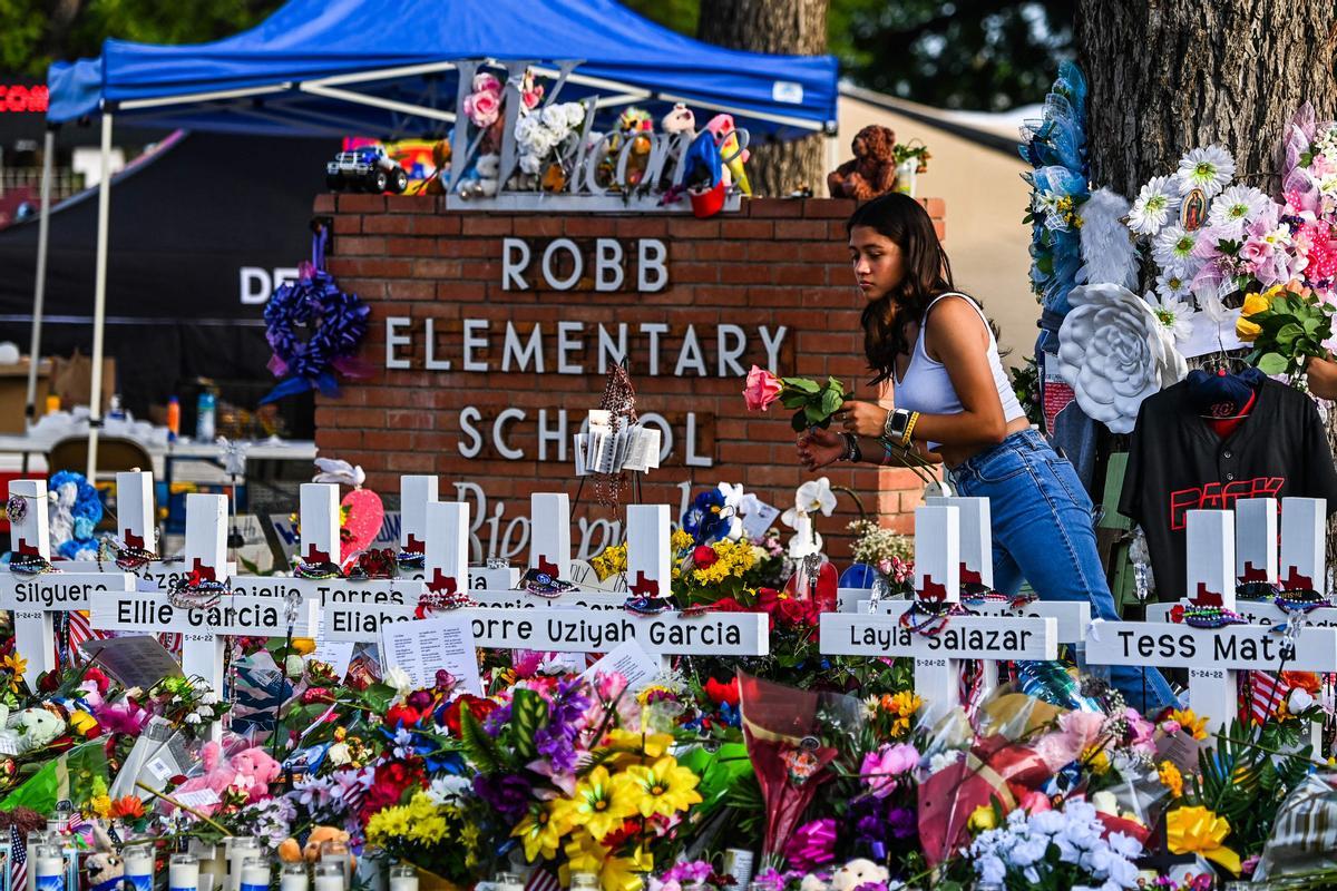 Una niña deposita flores en un memorial improvisado en la Escuela Primaria Robb en Uvalde, Texas, el 28 de mayo de 2022. (Foto de CHANDAN KHANNA / AFP)