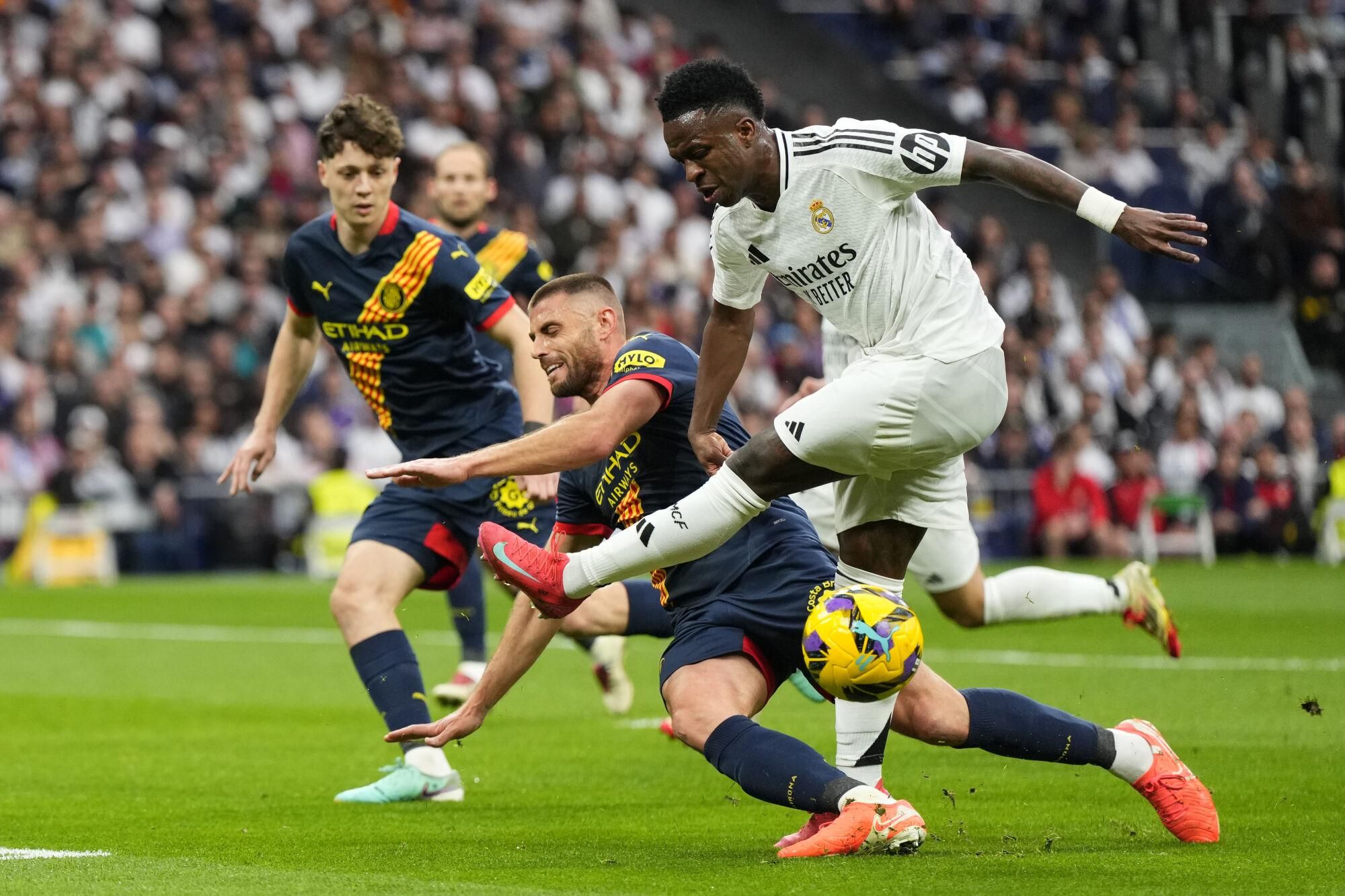 Real Madrid's Vinicius Junior, right, and Girona's David Lopez challenge for the ball during the Spanish La Liga soccer match between Real Madrid and Girona at the Santiago Bernabeu stadium in Madrid, Spain, Sunday, Feb. 23, 2025. (AP Photo/Manu Fernandez). EDITORIAL USE ONLY/ONLY ITALY AND SPAIN