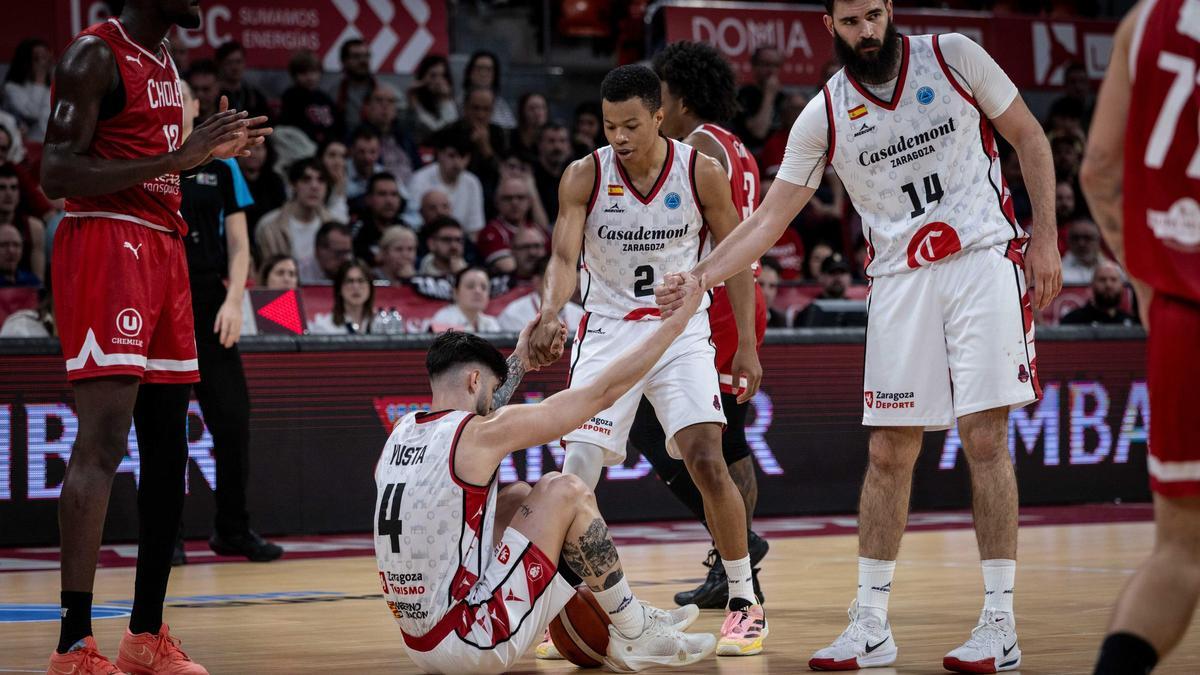 Trae Bell-Haynes y Bojan Dubljevic ayudan a levantarse del suelo a Santi Yusta en el partido frente al Cholet