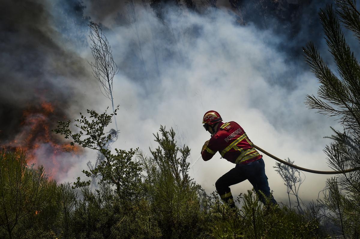 Un bombero combate un incendio forestal en el pueblo de Lavradio, Ourem, Portugal, 13 de julio de 2022. Dieciséis de los 18 distritos de Portugal continental están bajo aviso rojo, el más grave, debido al clima cálido, con más de cien condados en máximo peligro de incendio rural. (Incendio) EFE/EPA/NUNO ANDRE FERREIRA