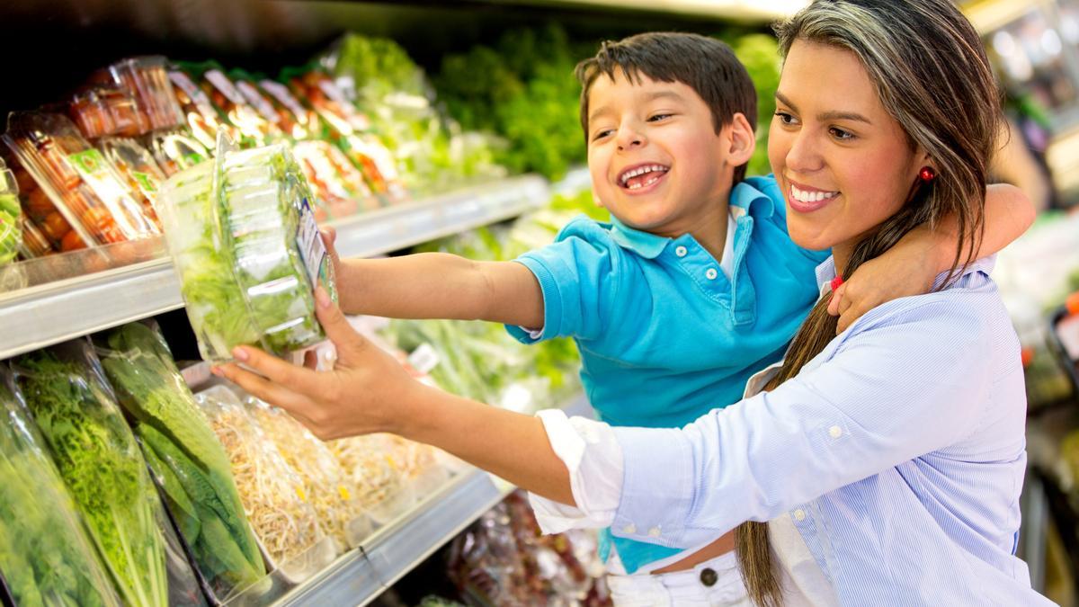 Un madre comprando alimentos saludables con su hijo.