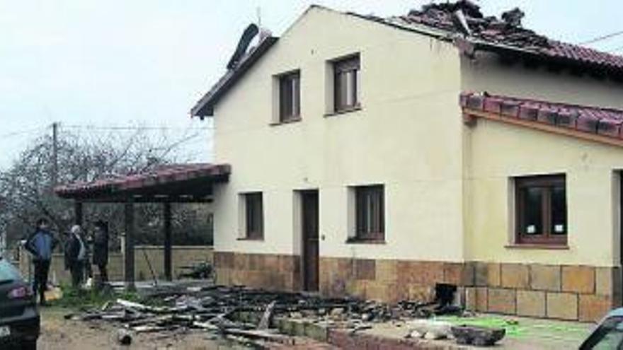 Varios vecinos observan el estado de la vivienda incendiada.