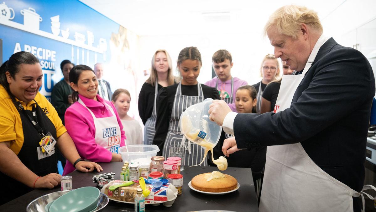 Britain's Home Secretary Priti Patel (2nd L) and Britain's Prime Minister Boris Johnson (R) try their hands at baking during a visit to the HideOut Youth Zone on the morning of the first day of the annual Conservative Party Conference being held at the Manchester Central convention centre in Manchester, north-west England on October 3, 2021. (Photo by Stefan Rousseau / POOL / AFP)