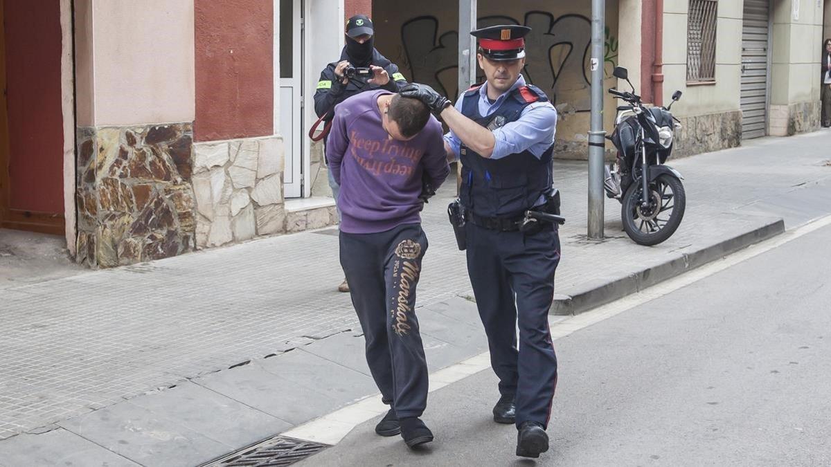 Un mosso conduce a uno de los dos detenidos por la desaparición de Janet Jumillas al coche policial.