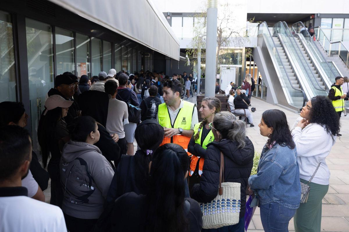 Personal de servicios sociales que informa a personas en la cola para tramitar su informe de vulnerabilidad en Ibiza.