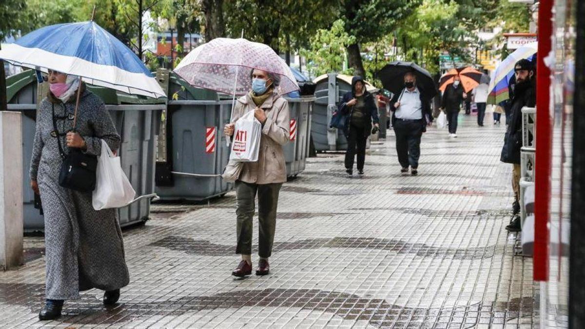 Ciudadanos por una calle de Extremadura protegiéndose de la lluvia con paraguas.